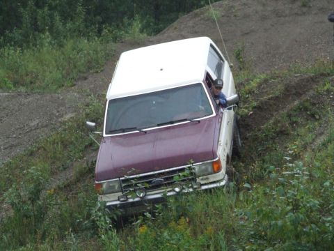 1990 Ford Bronco - 1990 Ford Bronco navigating a steep, overgrown dirt trail.