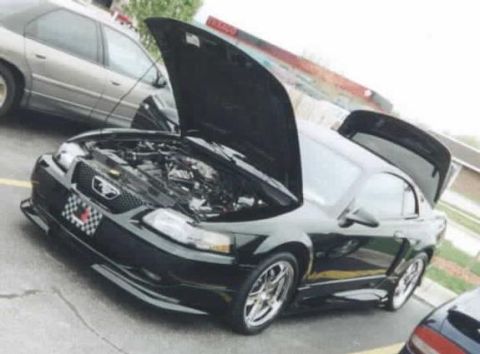 2001 Ford Mustang - A black Ford Mustang is parked with its hood and trunk open, revealing the engine bay.