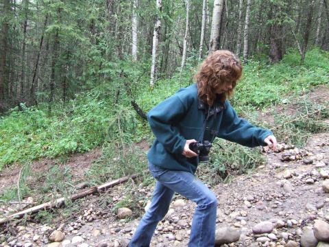 1990 Ford Bronco - A person walks through a wooded area with a camera, navigating a rocky, uneven terrain.