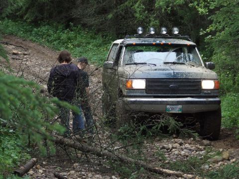 1990 Ford Bronco - Ford Bronco navigating a rough, forested path with two observers present.