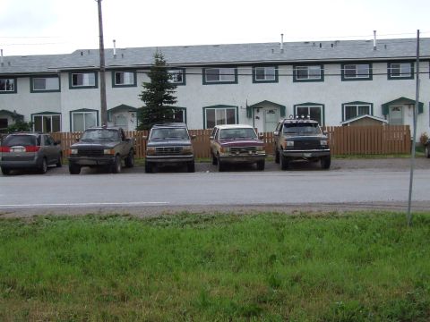 1988 Ford Bronco - Four SUVs are parked in front of a row of townhouses. One is a maroon Ford Bronco.
