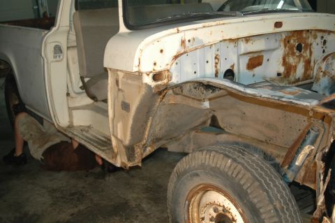 1963 Ford F-250 - A person works on the rusty chassis of a white pickup truck, revealing its internal structure and worn components.