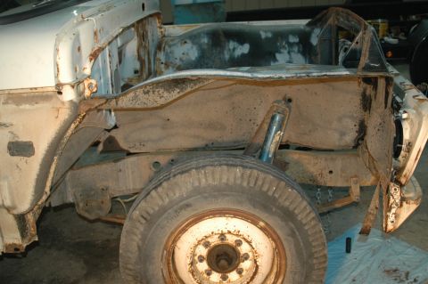 1963 Ford F-250 - The side view of a heavily rusted 1963 Ford F-250 chassis and wheel, indicating significant wear and tear.