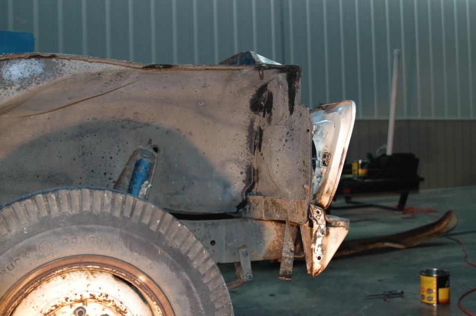 rusted truck fender, wheel, and part of the frame, showing damage and disrepair