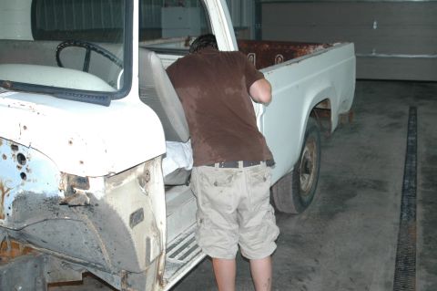 1963 Ford F-250 - A person works on the interior of a white pickup truck, likely from the 1960s.