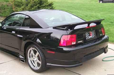 2001 Ford Mustang - The rear of a black Ford Mustang is shown parked on a driveway with a grassy area in the background.