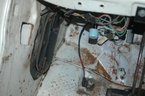 1963 Ford F-250 - Close-up view of the interior floor and exposed wiring of a vehicle, showing signs of rust and wear.