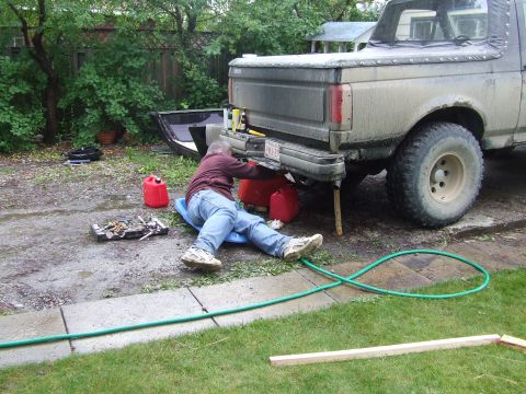 1990 Ford Bronco - A person works on the rear of a gray Ford Bronco in a yard.