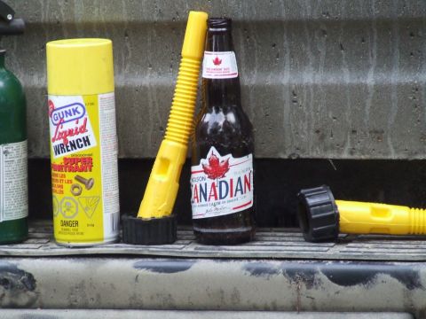 1990 Ford Bronco - A collection of items including a can of GUNK Liquid Wrench, a bottle of Molson Canadian beer, and yellow fuel spouts are arranged on a dir…