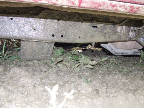 1990 Ford Bronco - The vehicle's frame and undercarriage are heavily coated in mud, suggesting it has been driven through difficult terrain.