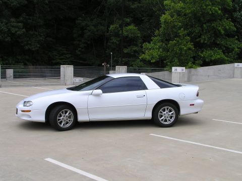 2001 Chevrolet Camaro - A white 2001 Chevrolet Camaro is parked in an outdoor lot with trees in the background.