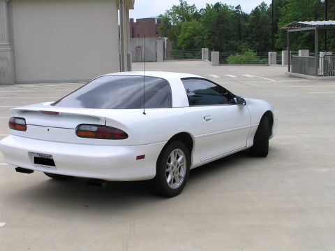 2001 Chevrolet Camaro - A white Chevrolet Camaro is parked in an outdoor lot, showing its rear profile and spoiler.