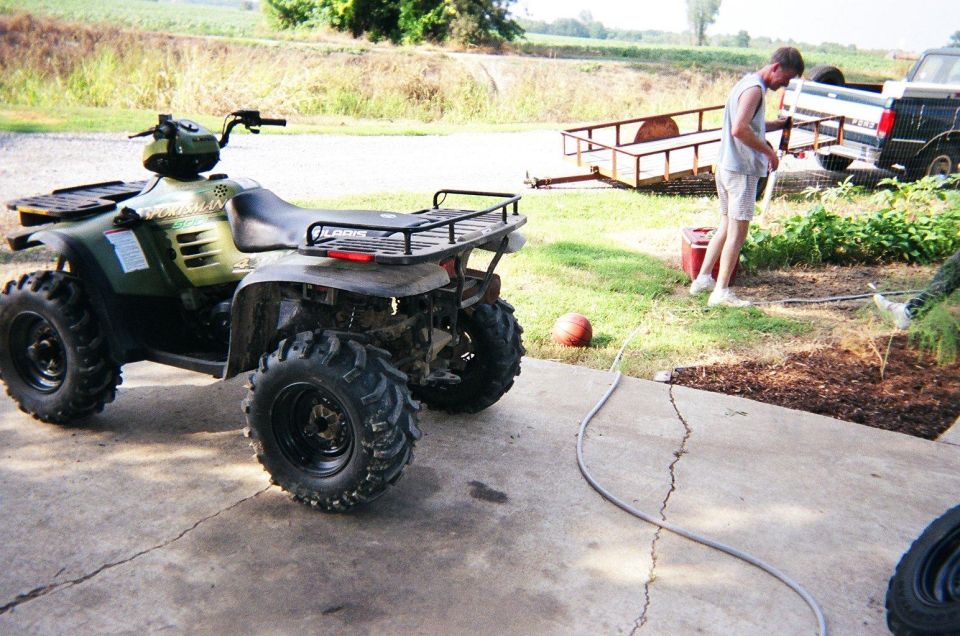 Green ATV parked on concrete, rear view