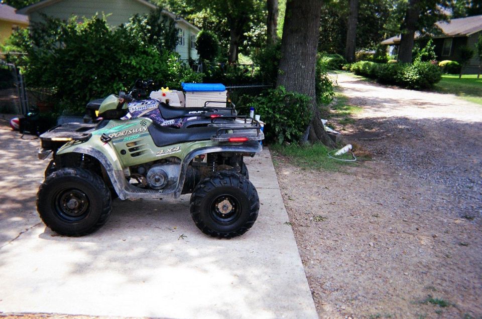 Green Polaris Sportsman 4x4 ATV parked on a concrete driveway
