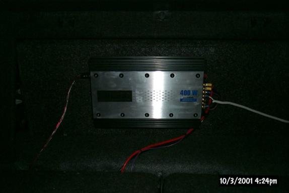 400-watt car amplifier mounted on carpeted trunk board with power and RCA wiring