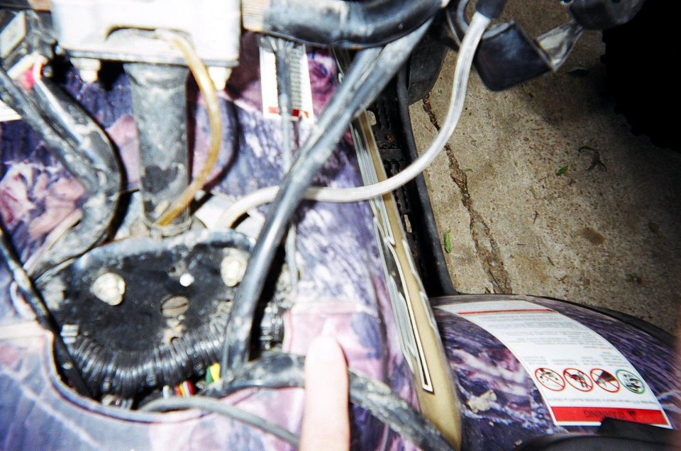 Close-up of ATV wiring and purple camouflage body panel with warning labels