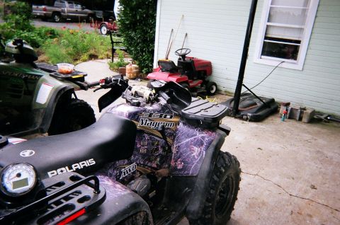 1995 Ford Bronco - A pair of all-terrain vehicles and a riding lawnmower are visible in a yard setting.