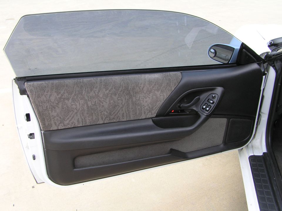 Interior door panel of a 2001 Chevrolet Camaro, showing textured fabric and power window controls