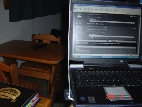 2005 Dodge 1500 - A laptop displays a web forum with discussion threads, next to a wooden table and chairs.