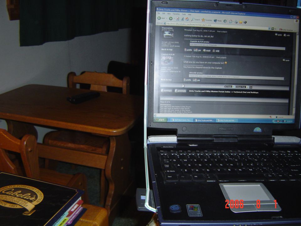 Laptop open on a table, showing a web forum. A wooden table and chairs are in the background