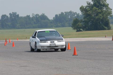 1992 Ford Taurus - A white 1992 Ford Taurus with a black hood and racing number 59 on the windshield drives through a cone course.