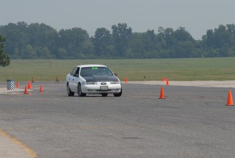 1992 Ford Taurus - A white 1992 Ford Taurus with a black hood navigates a course marked by orange cones.
