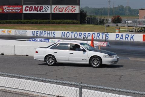 1992 Ford Taurus - White 1992 Ford Taurus with a black hood driving on a racetrack at Memphis Motorsports Park.