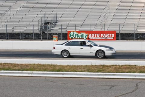 1992 Ford Taurus - White 1992 Ford Taurus with a black hood stripe seen on a race track with grandstands in the background.