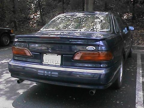 1993 Ford Taurus - Rear view of a dark blue sedan with SHO badging and a license plate.