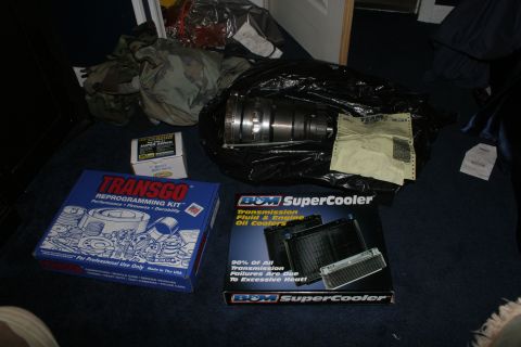 1989 Ford Crown Victoria LTD - Several automotive transmission parts are laid out on a dark carpeted floor.