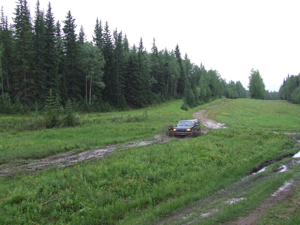 Dark SUV splashing through mud on a wooded trail