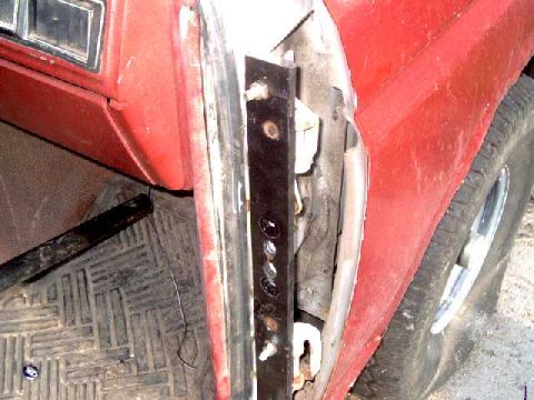 1986 Ford Bronco - Close-up view of a red vehicle's interior, focusing on the door frame and floor matting.