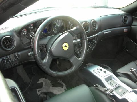 1998 Ford Crown Victoria - black leather interior of a Ferrari 360 shows its prancing-horse steering wheel, gauges and gated metal shifter.