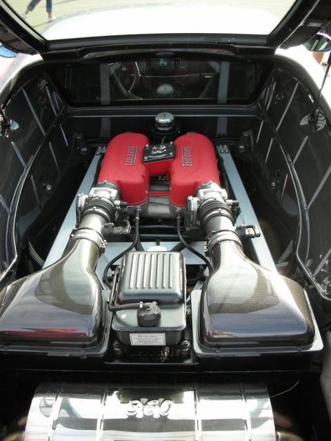1998 Ford Crown Victoria - mid-mounted engine of a Ferrari 360 shows red crackle-finish cam covers and twin intake plenums beneath glass.