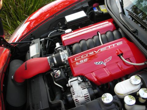 1998 Ford Crown Victoria - Engine bay of a Corvette showing red LS2 valve covers reading CORVETTE LS2 with a red intake tube and alternator.