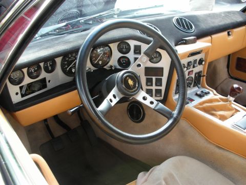 1998 Ford Crown Victoria - Interior of a Lamborghini with tan leather, black three-spoke steering wheel and a row of round gauges.