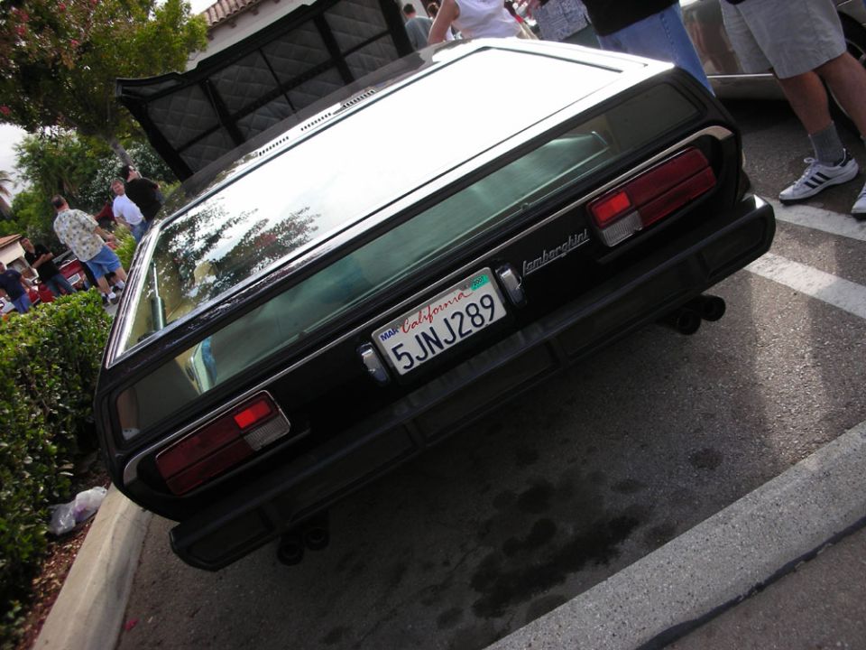 Rear of dark Lamborghini coupe with louvered window and California plate 5JNJ289