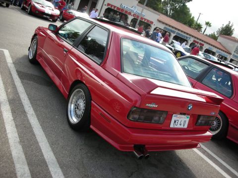 1998 Ford Crown Victoria - red BMW E30 M3 coupe shown from the rear three-quarter with BBS mesh wheels and vanity plate M34U.