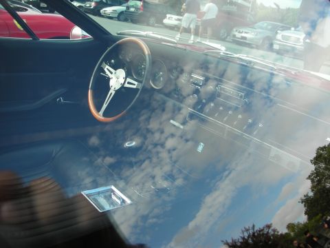 1998 Ford Crown Victoria - Interior of a classic car viewed through the windshield, showing a wood-rimmed steering wheel and dash amid sky reflections.