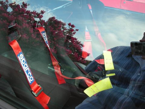 1998 Ford Crown Victoria - Red Sparco racing harness straps and a yellow tow strap visible through the windshield of a car.