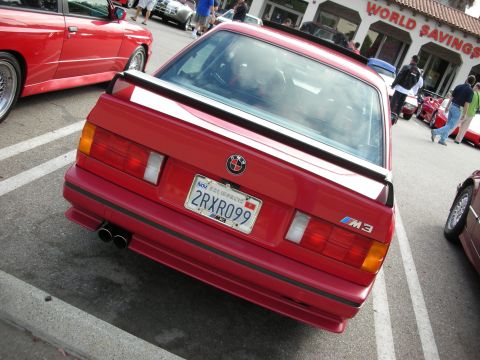 1998 Ford Crown Victoria - Rear view of a red BMW E30 M3 with its rear spoiler and California plate 2RXR099 at a car show.