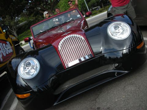 1998 Ford Crown Victoria - Front view of a low black-and-red custom roadster featuring a vertical mesh grille and skull-design inserts inside the round headlights.