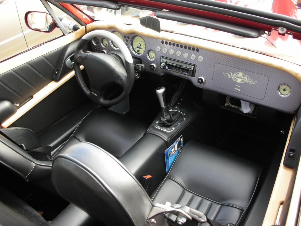 Black leather interior of a roadster with carbon-fiber dash and round gauges