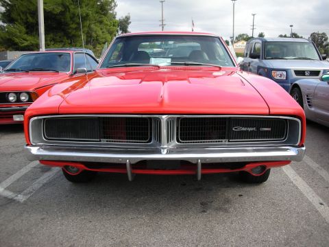 1998 Ford Crown Victoria - red Dodge Charger shows its split grille and Charger script badge head-on in a parking-lot car show.