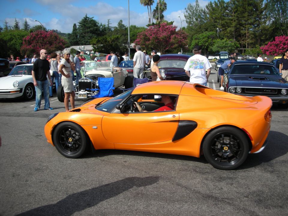 Side profile of an orange Lotus Elise at a crowded car show