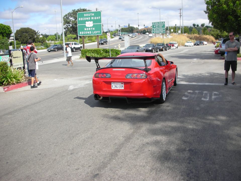 Rear of a red Toyota Supra with large wing at a street corner