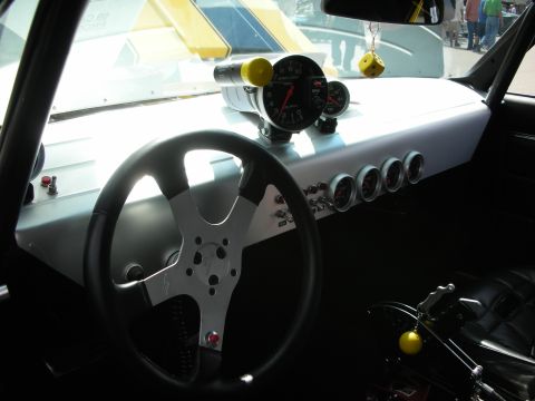 1998 Ford Crown Victoria - spartan race-style interior with a three-spoke wheel, dash-top tachometer and a row of toggle switches.