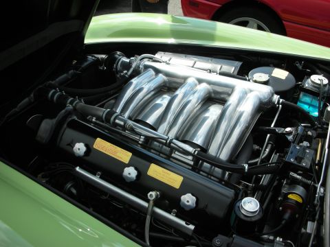 1998 Ford Crown Victoria - polished inline-six engine with sweeping intake runners sits in the bay of a pale green classic sports car.