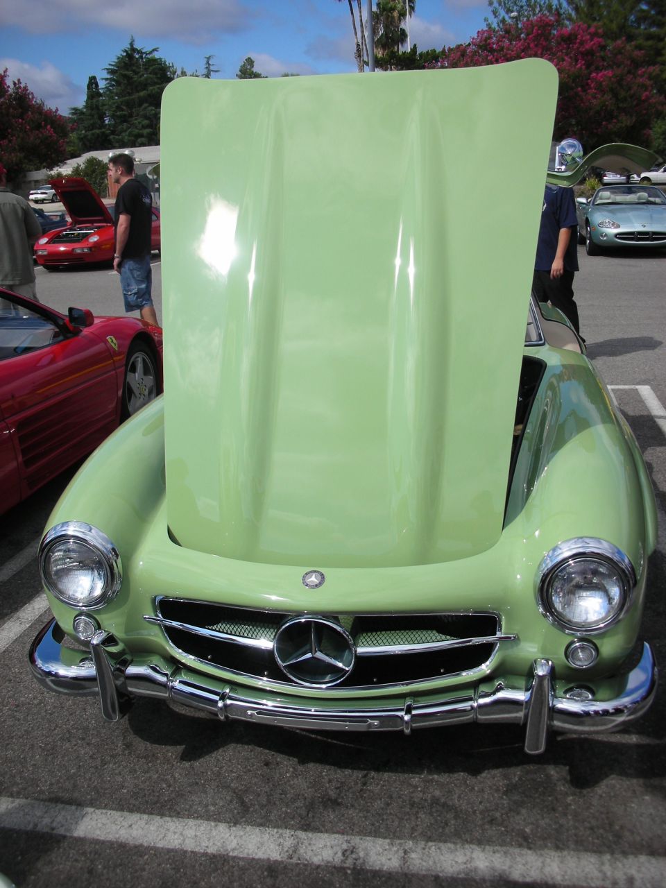 Front of a green Mercedes 300SL with hood raised at a car show