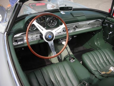 1998 Ford Crown Victoria - dark green leather interior of a Mercedes 300SL roadster, featuring a wood-rimmed steering wheel and chrome dash.